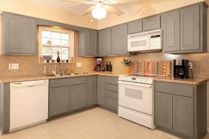 Gray cabinets in beige kitchen with white appliances