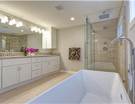 A bathroom with a bathtub, walk-in shower, and white vanity.