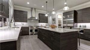 A modern kitchen with black cabinets, granite countertops, and drop light fixtures.